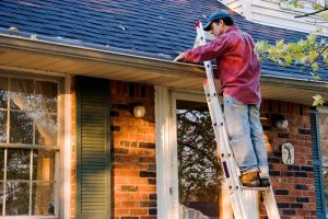 Man Cleaning His Gutters on Ladder