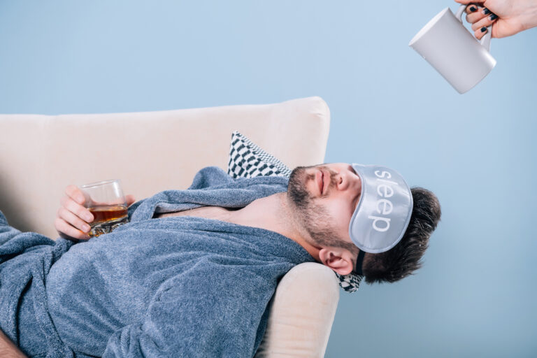 hungover man sleeping on couch with eye mask