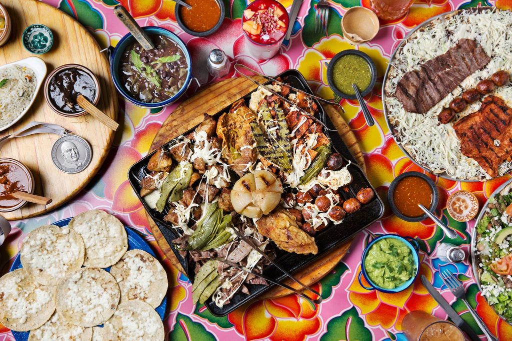 Variety of mexican food with chicken, steak, tortillas, salsa and guacamole